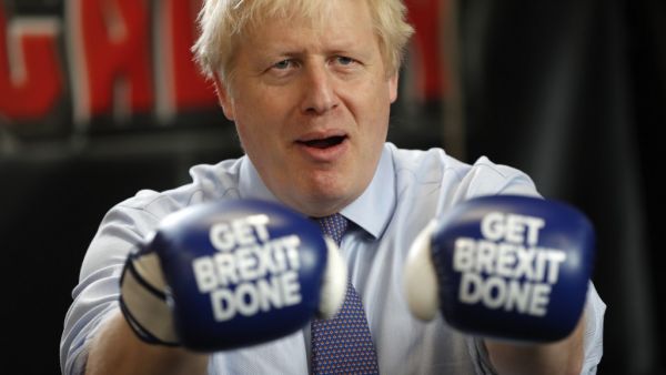 Britain's Prime Minister and leader of the Conservative Party, Boris Johnson wears boxing gloves emblazoned with "Get Brexit Done" as he poses for a photograph at Jimmy Egan's Boxing Academy in Manchester north-west England on November 19, 2019, during a general election campaign trip. Britain will go to the polls on December 12, 2019 to vote in a pre-Christmas general election. Frank Augstein / POOL / AFP