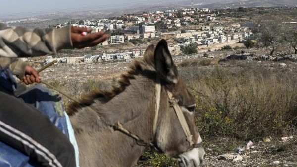 A man rides on a donkey in the Palestinian village of Kifl Hares opposite the Israeli Jewish settlement of Revava (background) on November 19, 2019. Israeli Prime Minister Benjamin Netanyahu hailed a US announcement that it no longer considers settlements in the West Bank and annexed east Jerusalem illegal, but the Palestinians pledged new measures to oppose it. Jaafar ASHTIYEH / AFP