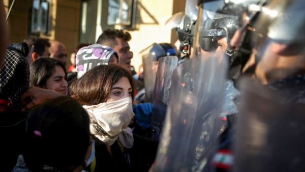Lebanese anti-government protesters face security forces during a demonstration near the parliament headquarters in the capital Beirut's downtown district on November 19, 2019. Lebanon's parliament, besieged by protesters, said it had indefinitely postponed a session that had been due to discuss controversial draft laws. "The session has been postponed to a date to be determined later," said parliament official Adnane Daher, reading a statement in front of television cameras, citing "exceptional conditions,