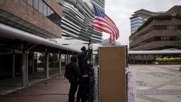 Protesters raise a US flag inside the Hong Kong Polytechnic University in the Hung Hom district of Hong Kong on November 20, 2019. A dwindling number of exhausted pro-democracy protesters barricaded inside the Hong Kong university defied warnings on November 19 to surrender, as a police siege of the campus stretched through a third day and China sent fresh signals that its patience with nearly six months of unrest was running out.