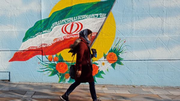 An Iranian woman walks past a mural painting of the Islamic republic's national flag in central Tehran on November 21, 2019. (AFP/ File Photo)
