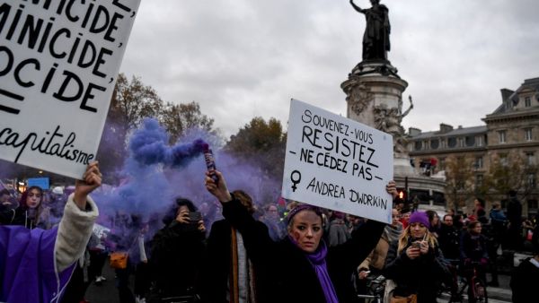 A woman holds a flare and a placard reading "Remember, resist, do not give in" during a protest to condemn violence against women, on November 23, 2019, in Paris. (Alain JOCARD / AFP)