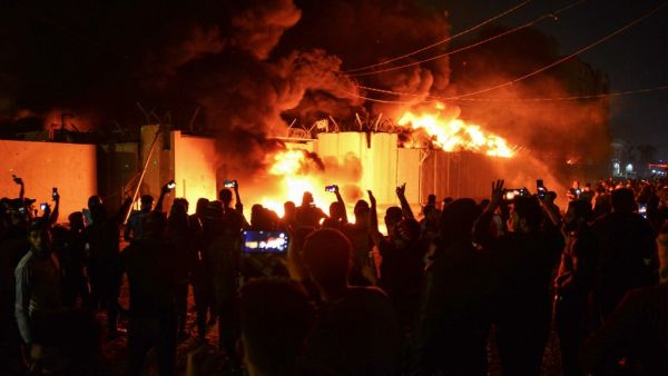 Iraqi demonstrators gather as flames start consuming Iran's consulate in the southern Iraqi Shiite holy city of Najaf on November 27, 2019, two months into the country's most serious social crisis in decades. Haidar HAMDANI / AFP