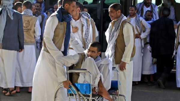A Yemeni Huthi prisoner on a wheelchair is helped by others November 28, 2019, upon his arrival at the airport of the capital Sanaa, following his release, along with other prisoners, by the Saudi-led coalition. (AFP/ File Photo)