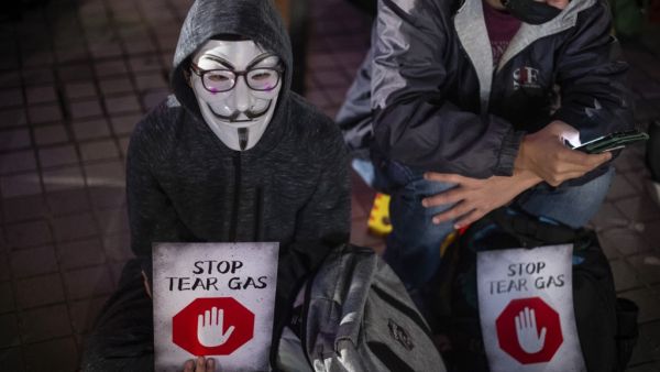 A participant wearing a Guy Fawkes mask holds a placard during a "Say no to tear gas" rally at Edinburgh place in Hong Kong on December 6, 2019. Philip FONG / AFP