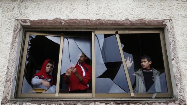 Palestinian boys pull shards of glass from a broken window at their home near the site of Israeli overnight attacks in Gaza City on December 8, 2019. (AFP/ File Photo)