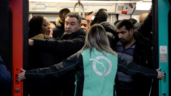 A Paris public transports operator RATP employee stands as commuters board on a RER B regional train at Chatelet-les Halles station in Paris on December 9, 2019 during a strike of RATP employees over French government's plan to overhaul the country's retirement system, as part of a national strike. (Aurore MESENGE / AFP)