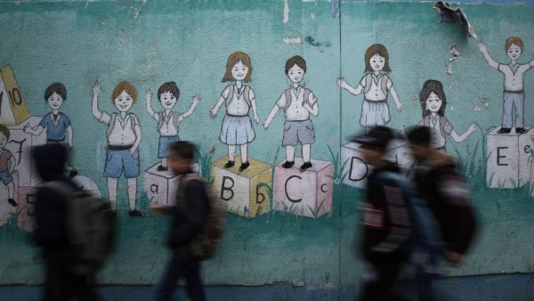 Palestinian children walk past a mural on their way to their United Nations-run school in Al-Shati refugee camp in Gaza City, on December 14, 2019. MOHAMMED ABED / AFP