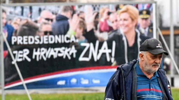 A man walks past a placard of the current Croatian President and candidate Kolinda Grabar-Kitarovic for the presidential election, from outside a window, in downtown Zagreb, December 21, 2019. Croatia voters will go to the polls on December 22, 2019 for the Croatian presidential election. Denis LOVROVIC / AFP
