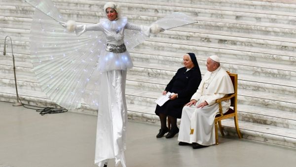 Pope Francis and Suor Antonietta Collacchi, director of the Santa Marta dispensary, look at a performer on stilts during an audience for children and families of the Santa Marta dispensary on December 22, 2019 at Paul-VI hall in the Vatican. Vincenzo PINTO / AFP