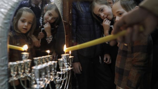 Ultra-Orthodox Jewish Krois family light candles on the first night of the Jewish holiday of Hanukkah in the Ultra-Orthodox Mea Shearim neighbourhood of Jerusalem on December 22, 2019. The holiday commemorates the rededication of the holy temple in Jerusalem after Jewish victory in 165 BC over the Hellenistic Seleucid armies of Antiochus IV Epiphanies, who had outlawed Jewish rituals and ordered Jews to worship Greek gods and adopt their customs. MENAHEM KAHANA / AFP