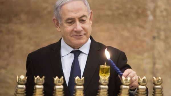 Israeli Prime Minister Benjamin Netanyahu lights a Hanukkah candle at the Western Wall, Judaism's holiest prayer site, in the Old City of Jerusalem on December 22, 2019. Sebastian Scheiner / POOL / AFP