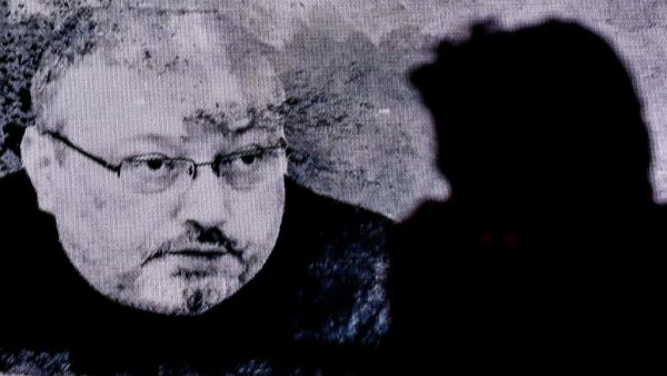 In this file photo taken on November 11, 2018 a man passes in front of a screen showing Jamal Khashoggi during a commemoration event of Khashoggi's supporters in Istanbul. Five people were sentenced to death on December 23, 2019, over Saudi journalist Jamal Khashoggi's murder, but two top aides to the powerful crown prince were exonerated as authorities said the killing was not premeditated. OZAN KOSE / AFP
