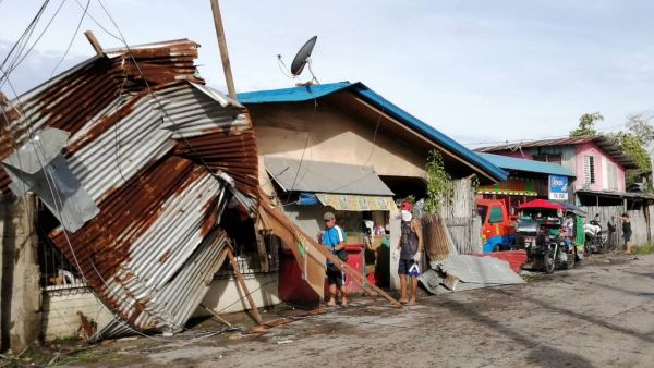 Residents stand next to a house damaged by typhoon Phanfone in Ormoc City, Leyte province in central Philippines on December 25, 2019. Typhoon Phanfone pummelled the central Philippines on December 25, bringing a wet, miserable and terrifying holiday season to millions in the mainly Catholic nation. RONALD FRANK DEJON / AFP