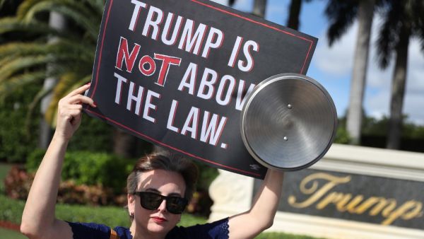 Aileen Ortega joins with other protesters outside of the Trump National Doral golf resort urging congress to impeach President Donald Trump (AFP)