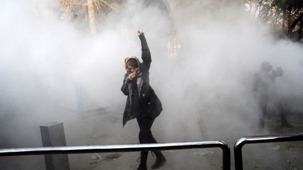 An Iranian woman raises her fist amid the smoke of tear gas at the University of Tehran during a protest driven by anger over economic problems, in the capital Tehran. (AFP/ File Photo)