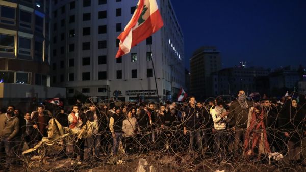 Lebanese anti-government demonstrators rally by barbed wire set by security forces to block a road leading to the government headquarters at the Grand Serail, in downtown Beirut, on January 25, 2020. ANWAR AMRO / AFP