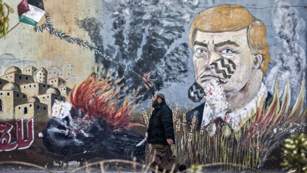 A Palestinian walks past a mural depicting US President Donald Trump with a footprint on his face, along a street in Gaza City (AFP)