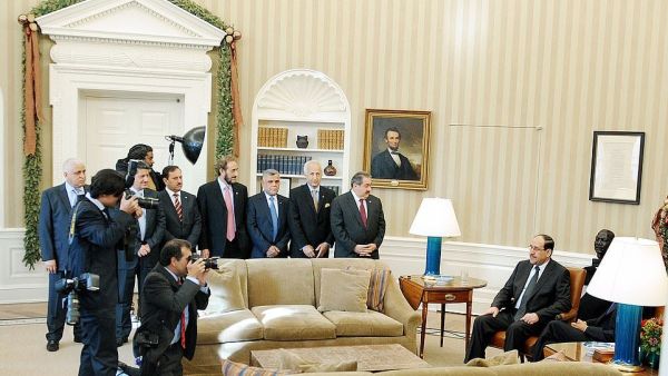 Prime Minister Nouri al-Maliki of Iraq and United States President Barack Obama (seated behind lamp) US President Barack Obama meets Prime Minister Nouri al-Maliki of Iraq at the Oval Office on December 12, 2011. Hadi al Amiri is seen behind the sofa, wearing a blue tie (Shutterstock)	