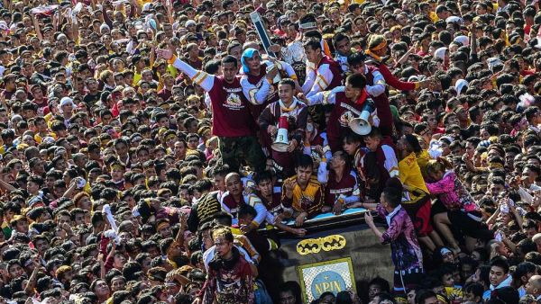 The display of religious fervor by largely poor Filipinos is one of the largest Catholic festivals in the world, and one of Asia's biggest religious events. Pictured: People climb on top of a statue of Black Nazarene as it parades through the streets  (AFP)