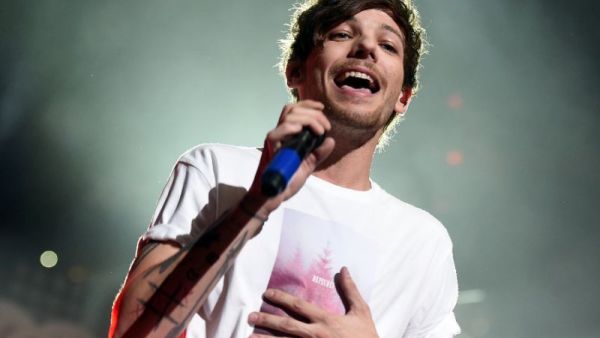 Singer Louis Tomlinson was in the baggage claim at Los Angeles International Airport with a girlfriend when he entered a tussle with a photographer (AFP Photo/KEVIN WINTER)