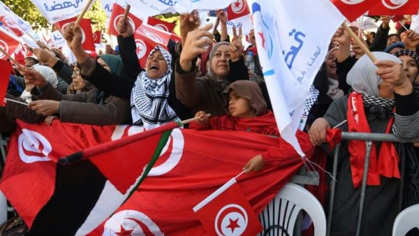 Tunisians wave their national flag and the flag of the Ennahda Islamist party as they gather on Habib Bourguiba Avenue in Tunis on January 14, 2018. AFP