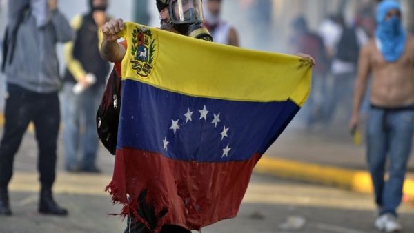 TORN. An anti-government student holds a torn Venezuelan flag during a protest in Caracas on February 15, 2014. Juan Barreto/AFP