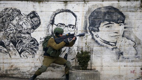An Israeli soldier fires teargas towards Palestinian demonstrators during a demonstration in al-Aroub Palestinian refugee camp, between the West Bank towns of Hebron and Bethlehem, on January 29, 2020. US President Donald Trump unveiled his controversial Israeli-Palestinian peace deal that staunchly favours Israel but offers Palestinians a pathway to a limited state. HAZEM BADER / AFP