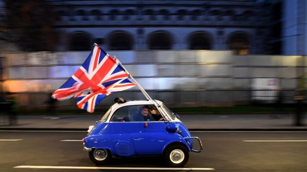 A man waves Union flags from a BMW Isetta as he drives past Brexit supporters gathering in Parliament Square, in central London on January 31, 2020, the day that the UK formally leaves the European Union. Britain on January 31 ends almost half a century of integration with its closest neighbours and leaves the European Union, starting a new -- but still uncertain -- chapter in its long history. DANIEL LEAL-OLIVAS / AFP