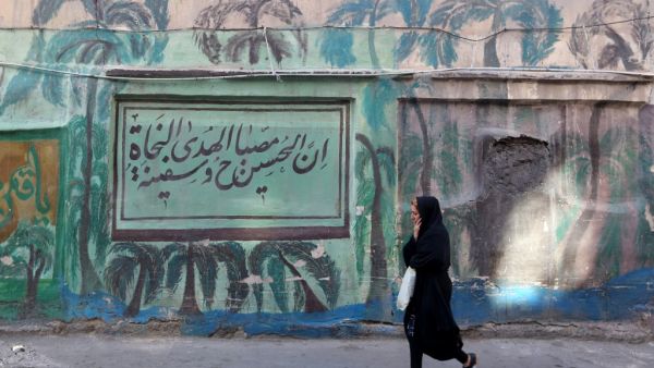 An Iranian woman walks past a mural in the southern Tehran district of Molavi on February 9, 2020. In a country weighed down by sanctions, shaken by protests and stressed by military tensions with the United States, many Tehranis struggle to hide their pessimism. ATTA KENARE / AFP