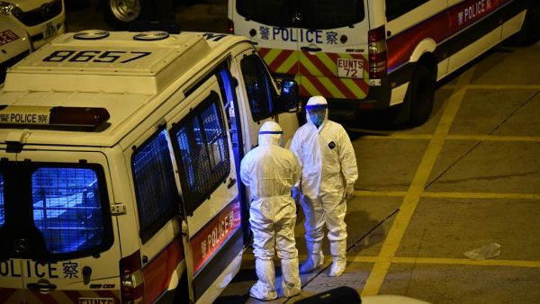 Police officers wearing protective suits stand next to their vans in the ground of a residential estate, in Hong Kong, early on February 11, 2020, after two people in the block were confirmed to have contracted the coronavirus according to local newspaper reports. Anthony WALLACE / AFP