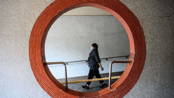 A resident wearing a face mask walks outside Hong Mei House at the Cheung Hong Estate in Hong Kong on February 11, 2020, following the evacuation of more than 100 people from the housing block after four residents in two different apartments tested positive for the new coronavirus. Officials said the relocation of residents in Tsing Yi district was a precautionary measure after three members of the same family contracted the virus. Anthony WALLACE / AFP