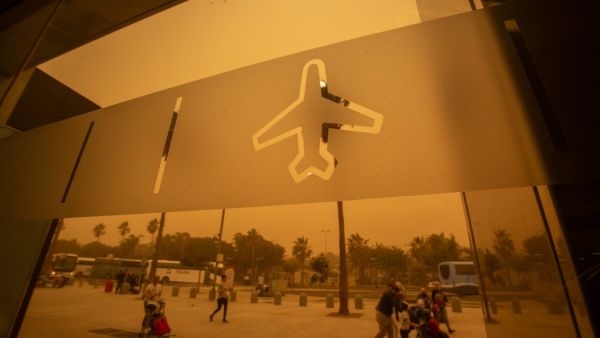 Passengers walk outside Tenerife South–Reina Sofia Airport during a sandstorm on February 23, 2020 on the Canary Island of Tenerife. Airports on Spain's Canary Islands were closed after strong winds carrying red sand from the Sahara shrouded the tourist hotspot.  DESIREE MARTIN / AFP