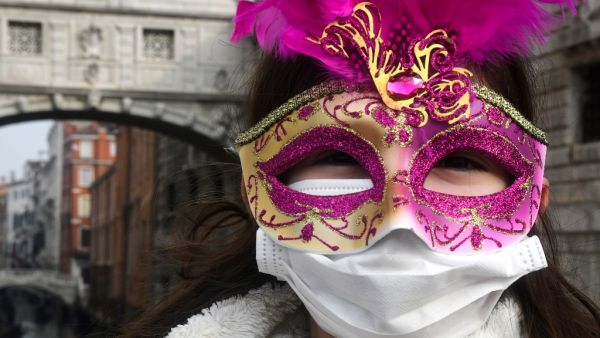 A young tourist wearing a protective facemask and a Carnival mask visits the streets of Venice, on February 24, 2020 during the usual period of the Carnival festivities which the last two days have been cancelled due to an outbreak of the COVID-19 the novel coronavirus, in northern Italy. Italy reported on February 24, 2020 its fourth death from the new coronavirus, an 84-year old man in the northern Lombardy region, as the number of people contracting the virus continued to mount. ANDREA PATTARO / AFP