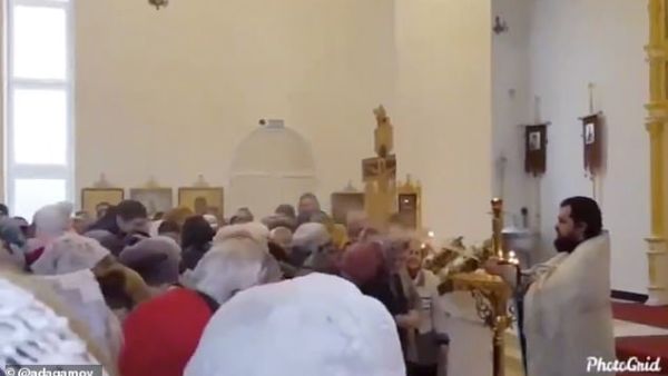 A Russian priest has been caught on camera hilariously spraying worshippers with holy water. (Video Screenshot)