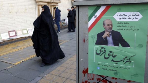 Extremists wanted. Iranians walk past an electoral poster of a candidate in the upcoming parliamentary elections on a street in Tehran on February 12. (AFP)