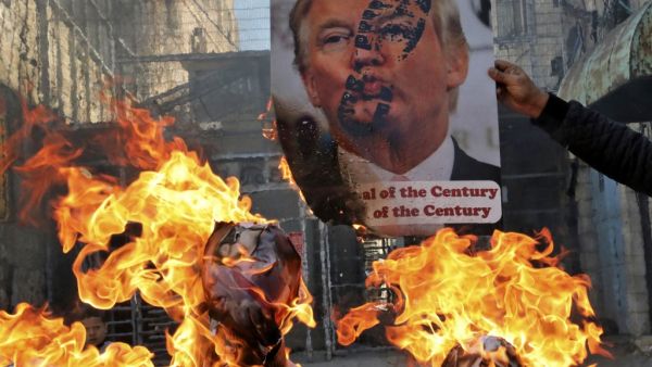 Demonstrators wave Palestinian flags as they burn effigies of US President Donald Trump and Israeli Prime Minister Benjamin Netanyahu during a protest against Trump's proposed Israeli-Palestinian peace plan, dubbed as the "deal of the century", outside an Israeli checkpoint in the flashpoint city of Hebron in the occupied West Bank on February 28, 2020. HAZEM BADER / AFP