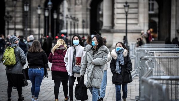 Tourists wearing a protective face mask amid fears of the spread of the COVID-19 novel coronavirus walk at the Pyramide du louvre area on February 28, 2020 in Paris. STEPHANE DE SAKUTIN / AFP