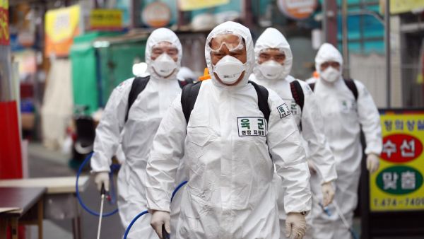 South Korean soldiers wearing protective gear spray disinfectant as part of preventive measures against the spread of the COVID-19 coronavirus, at a market in Daegu on March 2, 2020. South Korea reported nearly 500 new coronavirus cases on March 2, sending the largest national total in the world outside China past 4,000. YONHAP / AFP