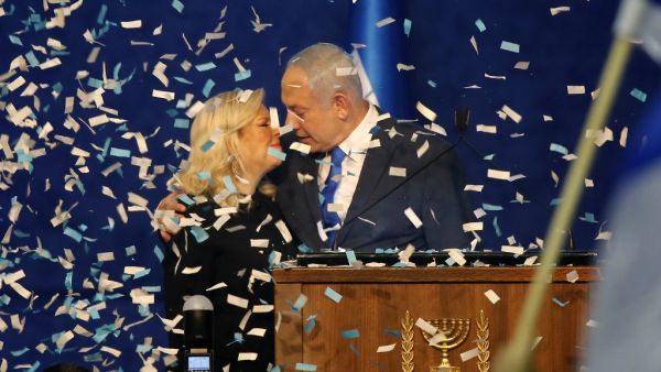 Israeli Prime Minister Benjamin Netanyahu approaches to kiss his wife Sara as confetti falls upon them while addressing supporters at the Likud party campaign headquarters in the coastal city of Tel Aviv early on March 3, 2020, after polls officially closed. Netanyahu claimed "a giant victory" in elections on March 3, boasting that his right-wing Likud party had defied "all expectations" in the country's third vote in less than a year. After exit polls by three networks forecast that Likud and its allies we
