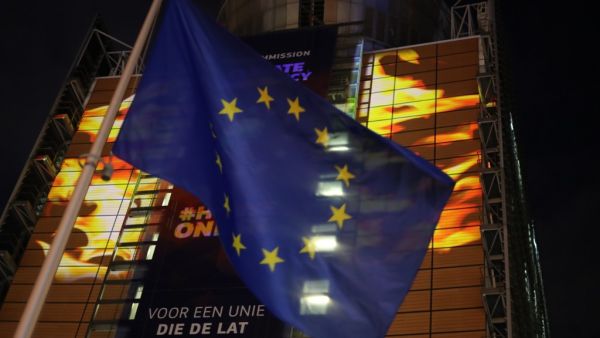 The European Union flag flies in front of images projected by activists from the environmental group Greenpeace showing Earth on fire onto the European Commission headquarters during a protest action on the eve of the presentation of the European Union climate law, in Brussels, on March 3, 2020. The EU Commission is due to introduce on March 4, 2020, its proposal for a "Climate Law" on climate neutrality in 2050. kenzo tribouillard / AFP