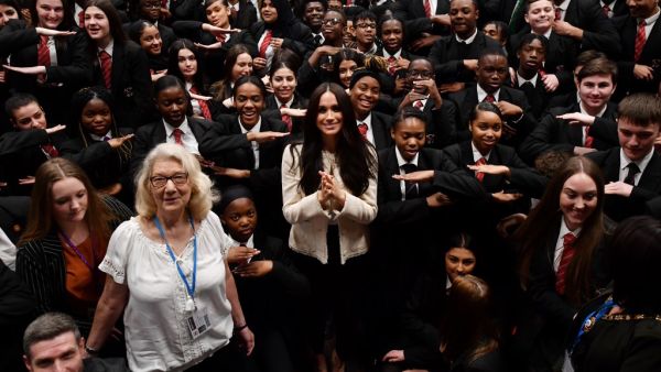 Britain's Meghan, Duchess of Sussex poses with school children making the 'Equality' sign following a school assembly during a visit to Robert Clack School in Essex, on March 6, 2020, in support of International Women’s Day. BEN STANSALL / POOL / AFP