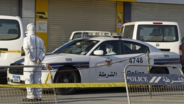 Bahraini policemen seal off a building housing foreign workers in the Salmabad industrial area as a precautionary measure after a resident tested positive for coronavirus (COVID-19), on the outskirts of the capital Manama on March 13, 2020. Mazen Mahdi / AFP