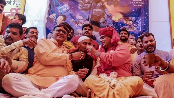 Hindu organisation 'Akhil Bharat Hindu Mahasabha' president Chakrapani Maharaj (2R) makes a supporter (C) drink panchagavya, a traditional Hindu ritual mixture made of cow dung, urine, milk, curd and ghee as they attend a 'gaumutra (cow urine) party' to fight against the spread of the COVID-19 coronavirus, in New Delhi on March 14, 2020. Jalees ANDRABI / AFP