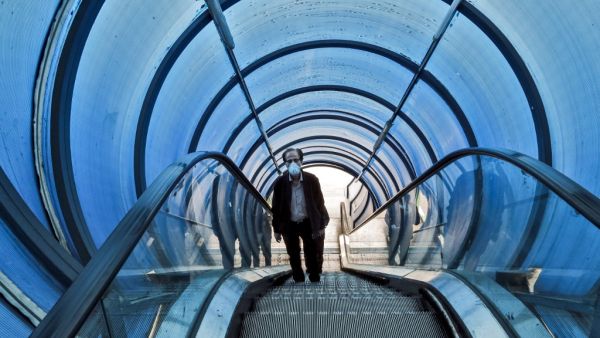 A man wearing a protective face mask rides the escalator of a pedestrian overpass bridge in Iran's capital Tehran on March 14, 2020. STRINGER / AFP