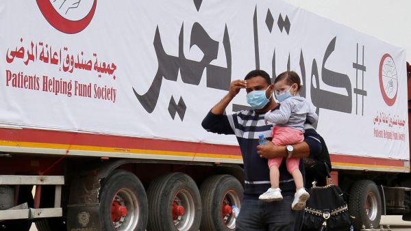 A man carries a toddler as they arrive at a Kuwaiti health ministry containment and screening zone for COVID-19 coronavirus disease for expatriates returning from Egypt, Syria, and Lebanon, in Kuwait City on March 15, 2020. YASSER AL-ZAYYAT / AFP
