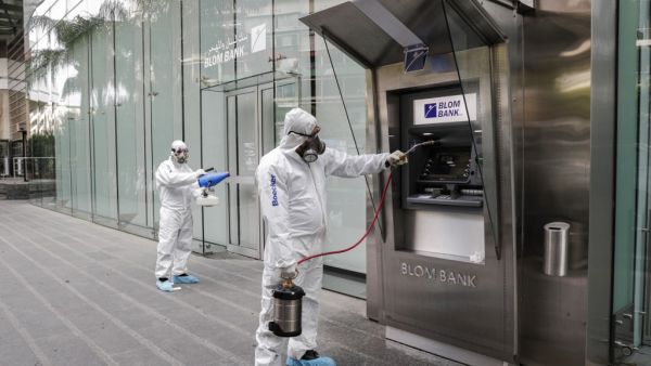 Employees of a private company spray sanitising liquid around a bank in a bid to limit the spread of the cornonavirus Civid-19, in the Lebanese capital Beirut on March 15, 2020. ANWAR AMRO / AFP