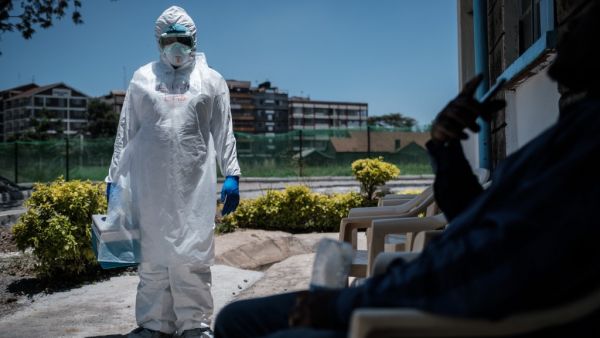 A laboratory specialist wearing protective gear speaks with a man asking to get tested in front of the ward for quarantined people who had close contacts with the first Kenyan patient of the COVID-19 at the Infectious Disease Unit of Kenyatta National Hospital in Nairobi, Kenya, on March 15, 2020. AFP