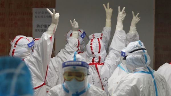 Medical staff cheer themselves up before going into an ICU ward for COVID-19 coronavirus patients at the Red Cross Hospital in Wuhan in China's central Hubei province on March 16, 2020. China reported 12 more imported cases of the novel coronavirus on March 16 as the capital tightened quarantine measures for international arrivals to prevent a new wave of infections. STR / AFP