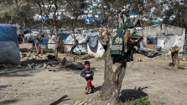 A young boy looks on as he walks at the unofficial camp net to the refugee camp of Moria in the island of Lesbos after a fire broke out, on March 16, 2020. Manolis Lagoutaris / AFP